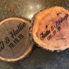 Two wooden slices with engraved names and dates on a textured surface